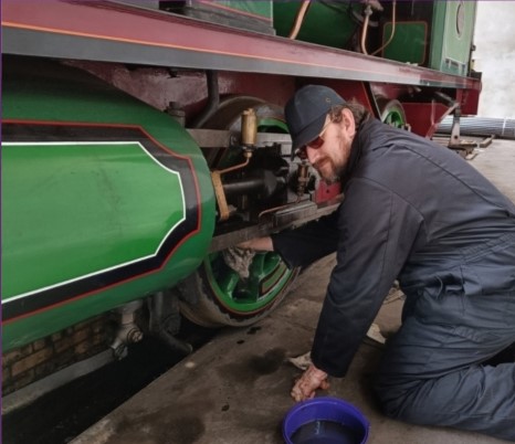 A volunteer cleaning parts of a steam train 