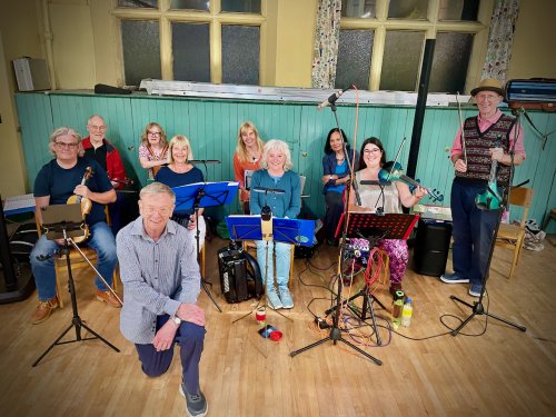 The Redheughers Ceilidh Band sitting with their instruments ready to perform