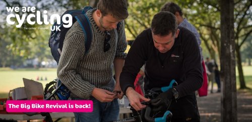 Man helping someone fix with their bike in a sunny park