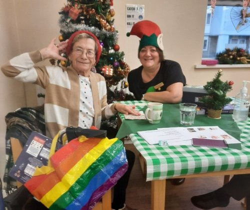 Two women in Christmas hats with a pride bag smiling