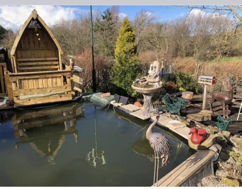 Photo shows a boat shaped shelter overlooking a pond with viewing platform to watch the fish 