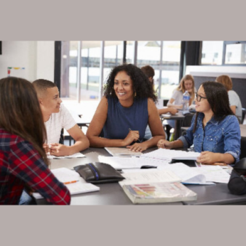 Group of people sat round a table engaging in an activity with paper and workbooks on the table