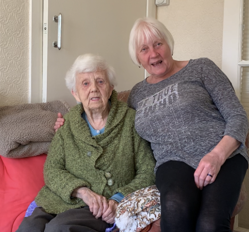 Two older ladies sitting smiling at the camera