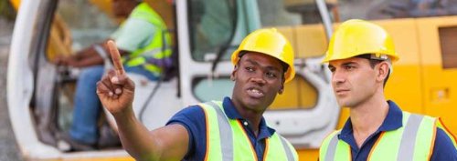 Two men in hard hats and Hi-Vis on a construction site