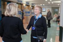 A volunteer smiling and greeting someone in the hospital.