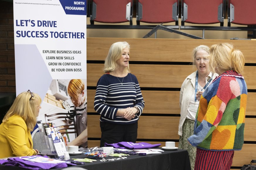 A photo of four people having a conversation at a business support booth.