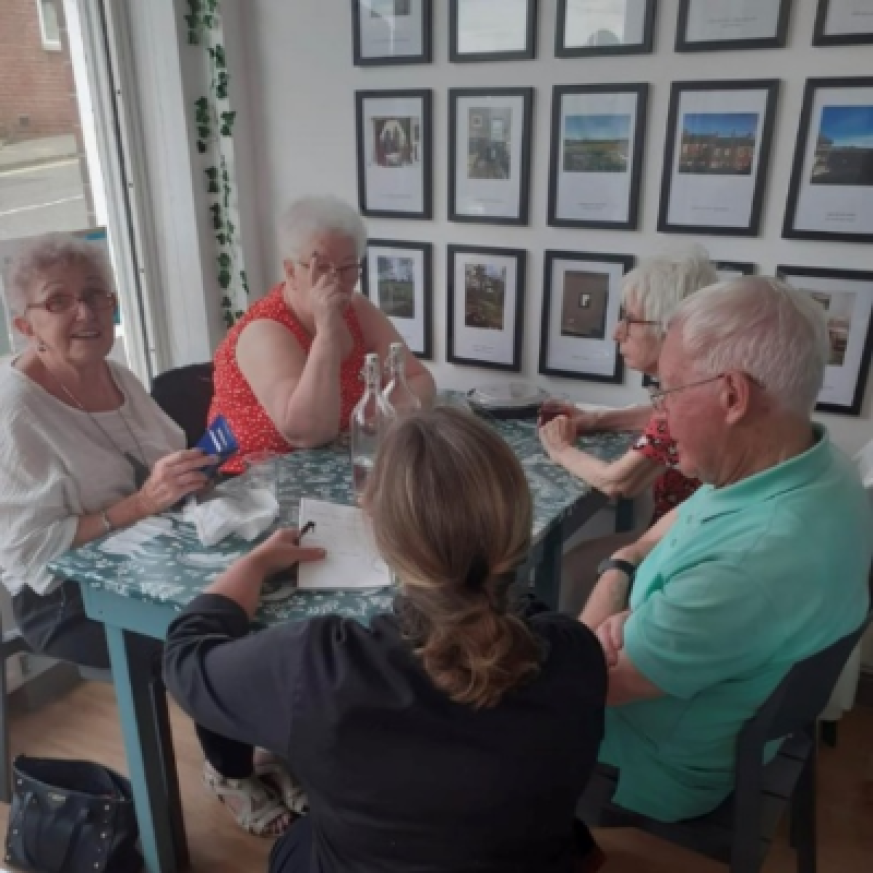 Older people sitting around a table in the Bank, enjoying a good story 