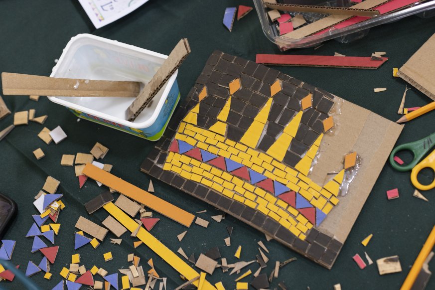 A photo of pieces of diferrent coloured mosaic. On the right, there is a half completed mosaic of a crown.