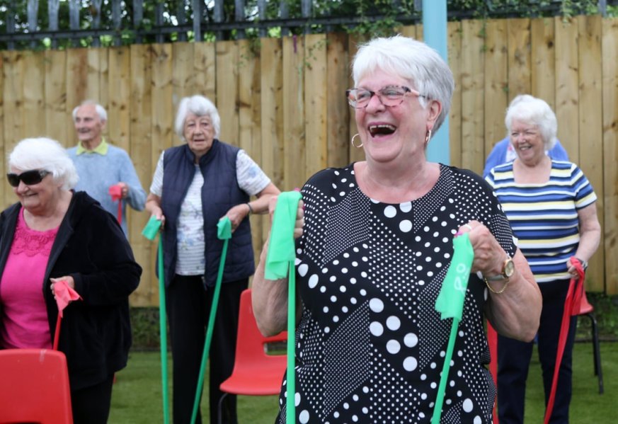 People laughing and using elastic exercise bands.