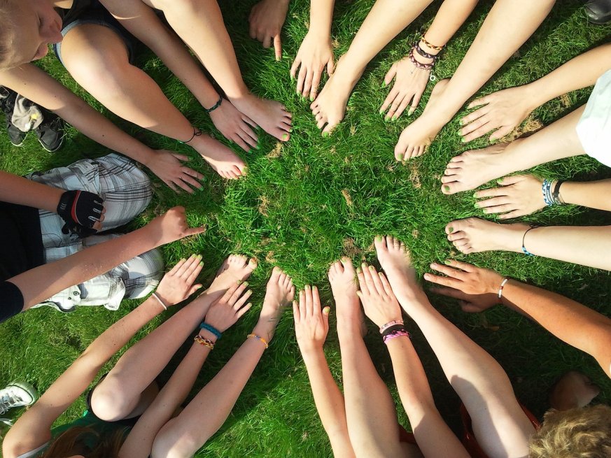 Group of women in a circle with their hands pointing towards the center
