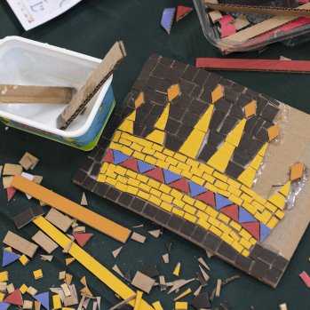 A photo of pieces of diferrent coloured mosaic. On the right, there is a half completed mosaic of a crown.