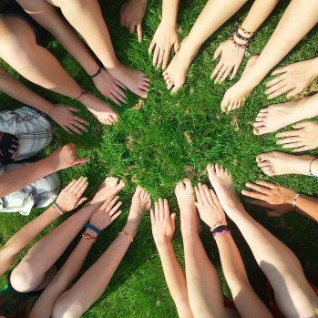 Group of women in a circle with their hands pointing towards the center