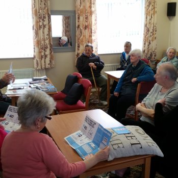 group of people sitting at tables talking and looking at leaflets
