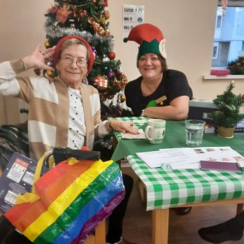 Two women in Christmas hats with a pride bag smiling
