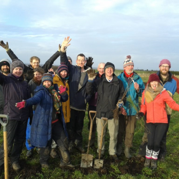 Group of volunteers standing outside in a field laughing and smiling at the camera